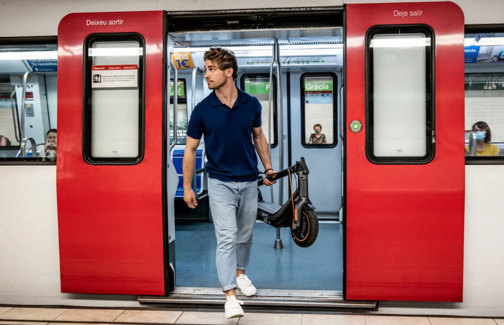 Мужчина выносит сложенный самокат из метро