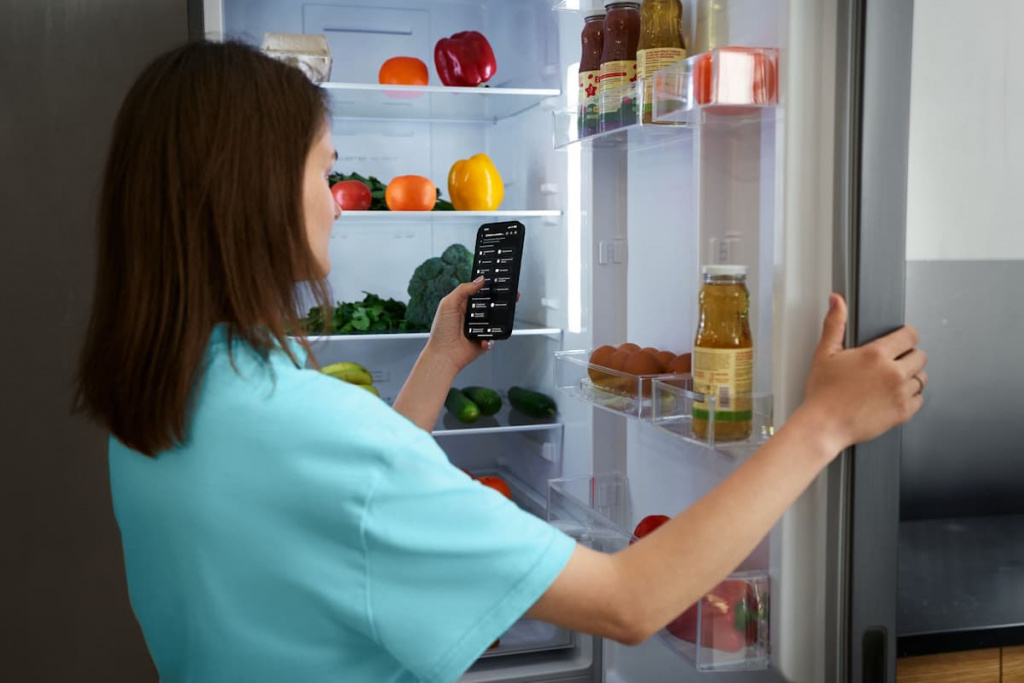 Девушка управляет холодильником со смартфона